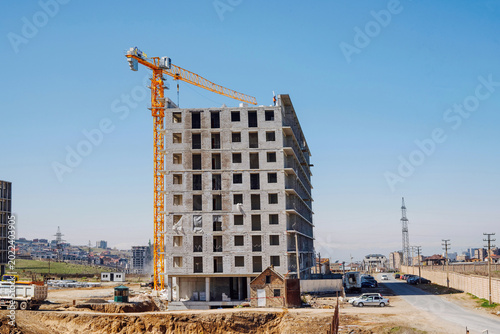 Fotografie Construction of monolithic residential building with yellow tower crane outdoor