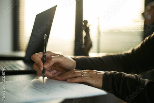 Canvas Print Close up of young adult woman signing divorce papers beside laptop, documenting legal separation and marital breakup