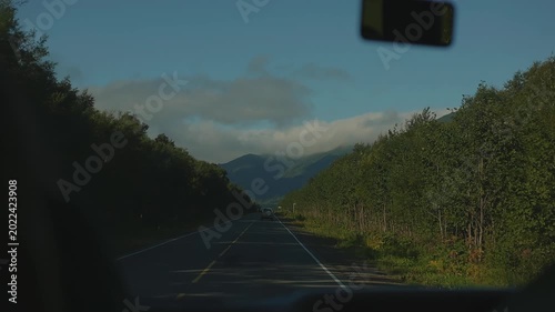 View through windshield of road with bus and cars and beautiful landscape with mountain ranges in haze.