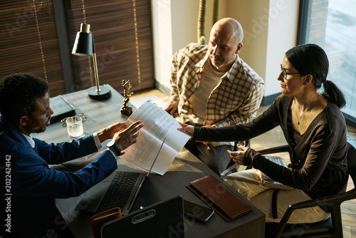 Foto Black male lawyer reviewing documents with middle aged couple during divorce consultation in office