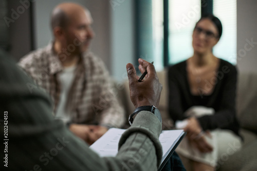 Photos Middle aged couple attending counseling session, listening during divorce mediation with therapist taking notes