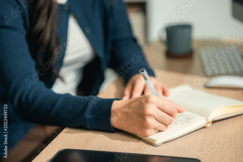Εκτύπωση καμβά Modern Asian woman sitting in a cozy room, thoughtfully journaling in her notebo