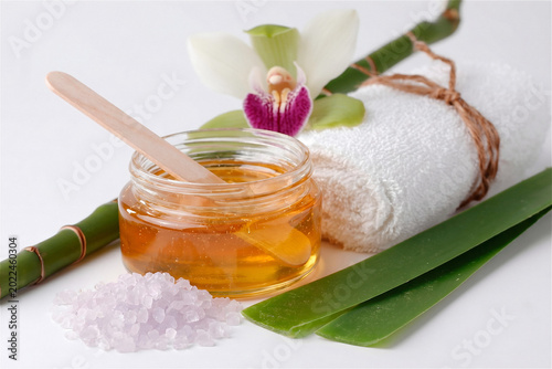 Wax jar for sugaring with wooden spatula, spa concept flat lay with orchid, aloe vera leaves and sea salt scrub - hair removal and depilation beauty salon commercial, copy space