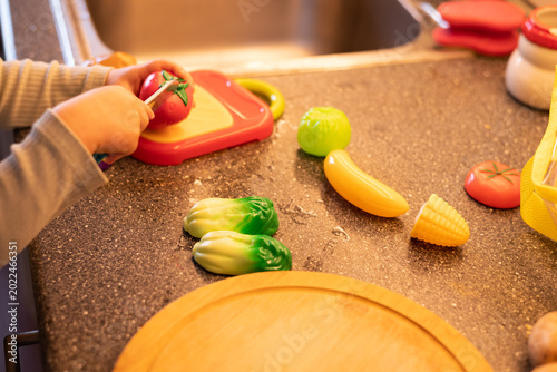 Bild auf Leinwand Cute toddler playing with toy vegetables in cozy home kitchen
