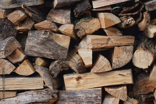 brown wood texture from heap of pine firewood against the wall in the street