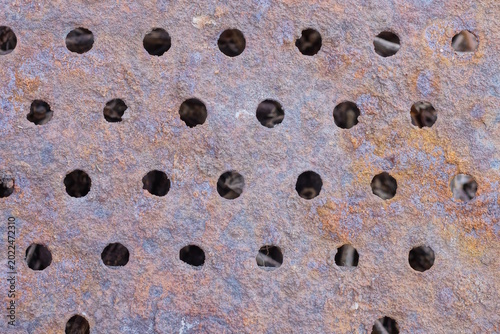 brown metal texture of rusty iron wall with a row of round holes