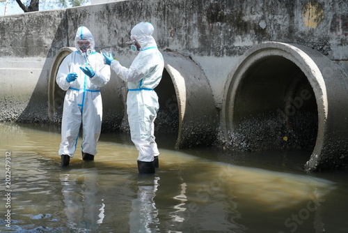 Two environmental scientists wearing PE chemical protective suits collected water samples from a tunnel to check water quality after wastewater was treated and discharged into the sea.