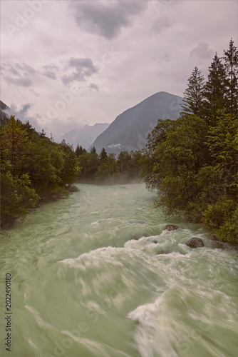Canvas Print Soca river green waters rush in the rain as they cross the Julian Alps, seen eastward upstream from the Za Otoki footbridge