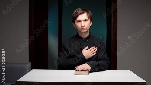 Canvas-taulu Man placing one hand on a book and the other over his heart, swearing an oath in