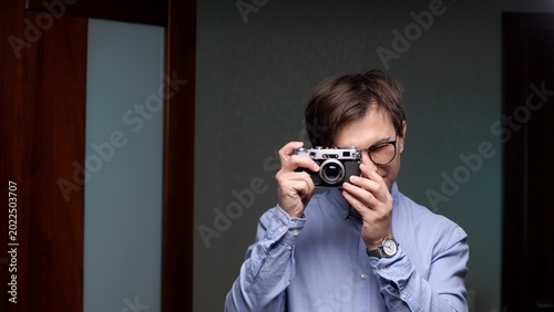 Foto Man in glasses holds a vintage film rangefinder camera, intently focusing to cap