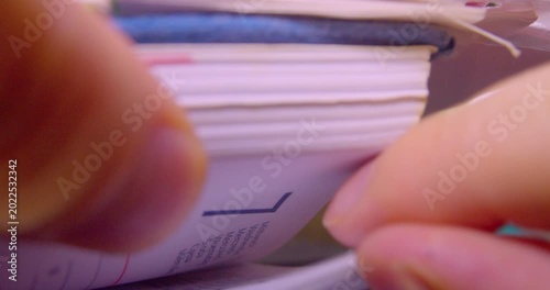 Paperwork in an office. Fingers flipping through a stack of documents. Searching for information. Macro photography.