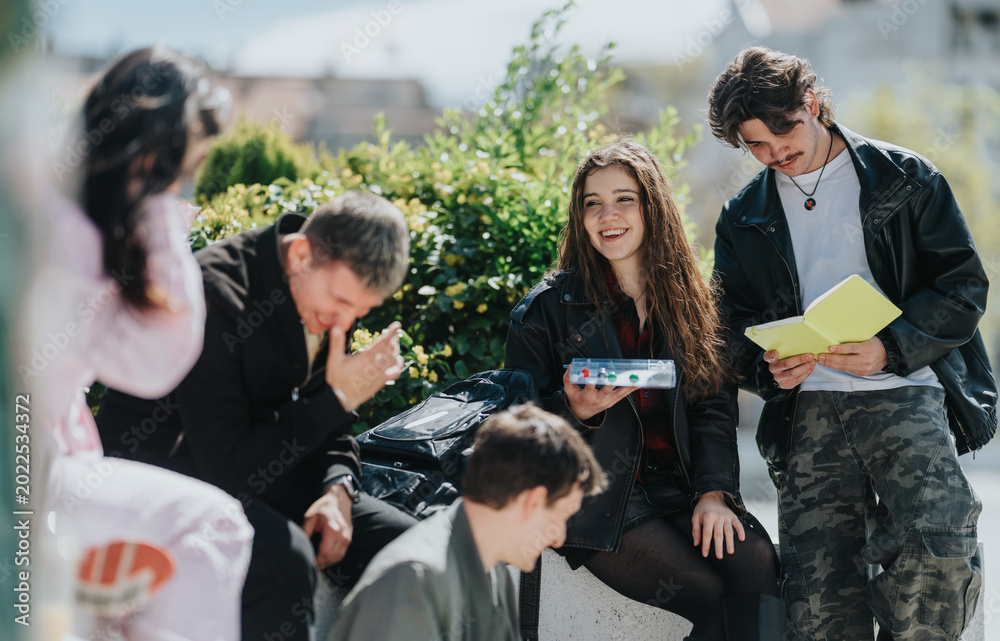 Obraz premium A group of high school friends and students sit together studying and laughing outdoors. Peers share a notebook and conversation while relaxing on a campus courtyard.