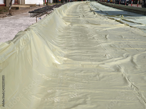 Fotografie Road construction site with concrete curing plastic sheet covering the ground