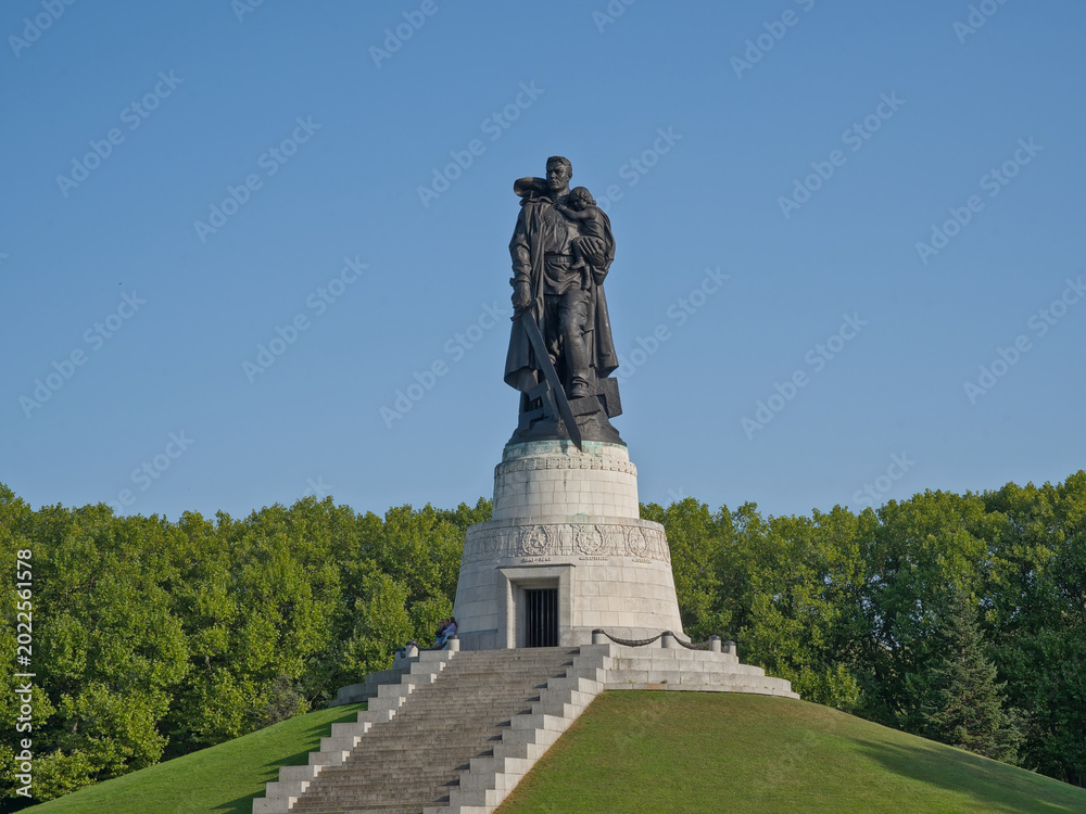 Obraz premium Sculpture of a soldier with a sword carrying a child, Soviet war memorial in Treptower park, Berlin, Germany