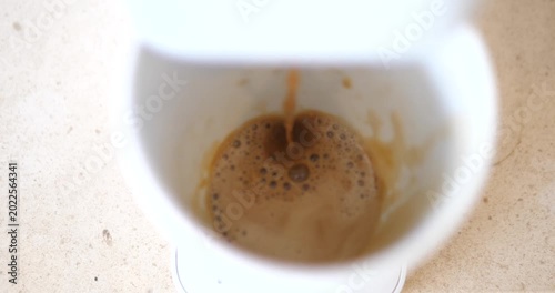 Cinematic top view of fresh hot espresso coffee extracting and dripping into a white ceramic cup, golden crema bubble texture close-up