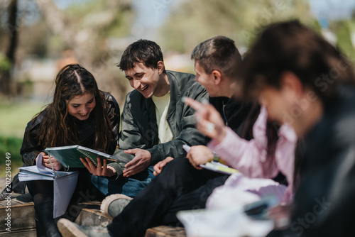 School friends sit on outdoor steps sharing notebooks and smiling as they study together. A group of students collaborate and laugh while reviewing notes in a park-like campus setting.
