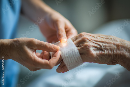 Caregiver Applying Bandage to Elderly Patient Hand in Close Up
