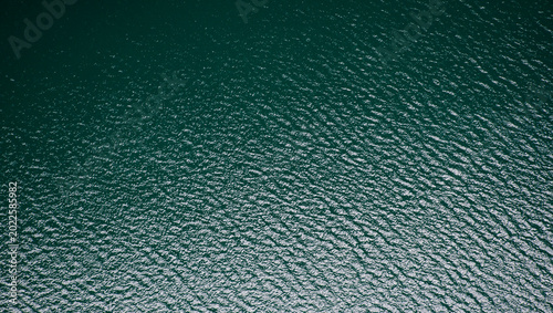 Photos Superficie acuática verde azulada, con ondulaciones suaves y reflejos de luz que evocan calma y movimiento continuo