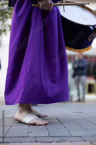 Foto Close-up of a barefoot penitent with bandaged feet playing a drum during a Holy Week procession in  Avilés, Asturias