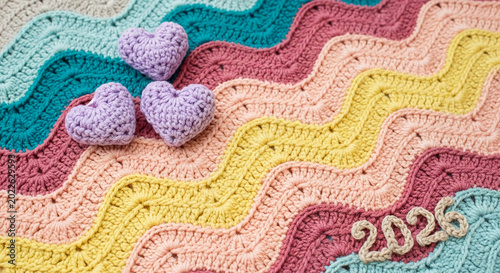 Crocheted blanket in pastel wavy stripes with purple hearts and 