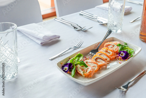 A platter with smoked salmon and soft cheese roulade on a table set for a party