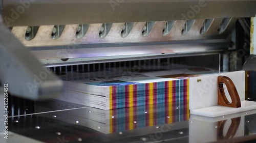 Industrial guillotine machine cutting paper stack in a printing factory