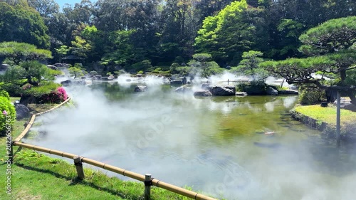 The artificial fog spreads beautifully over the large traditional pond in Ohori Park Japanese Garden in Fukuoka. A dense white mist covers the water surface creating scenic unkai sea of clouds effect