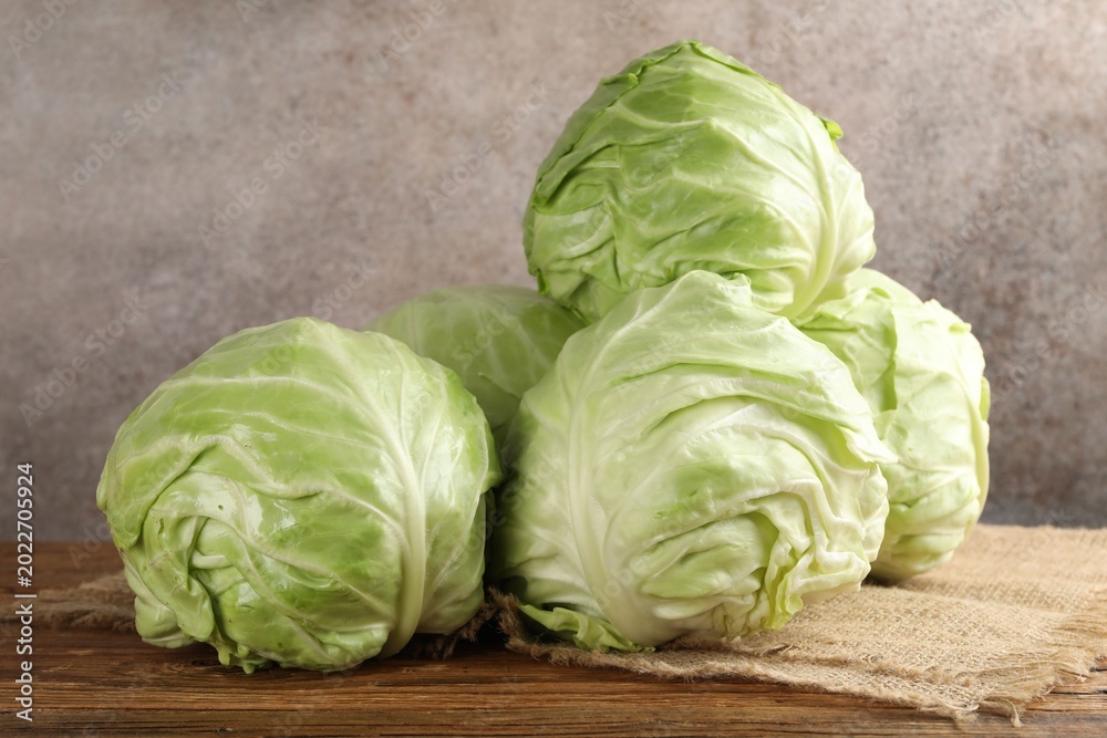 Fototapeta premium Fresh whole cabbages on wooden table, closeup