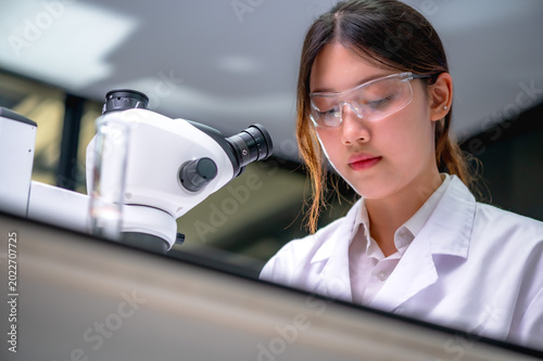 Fotografie Asian female scientist working at microscope doing research with Hantavirus pand