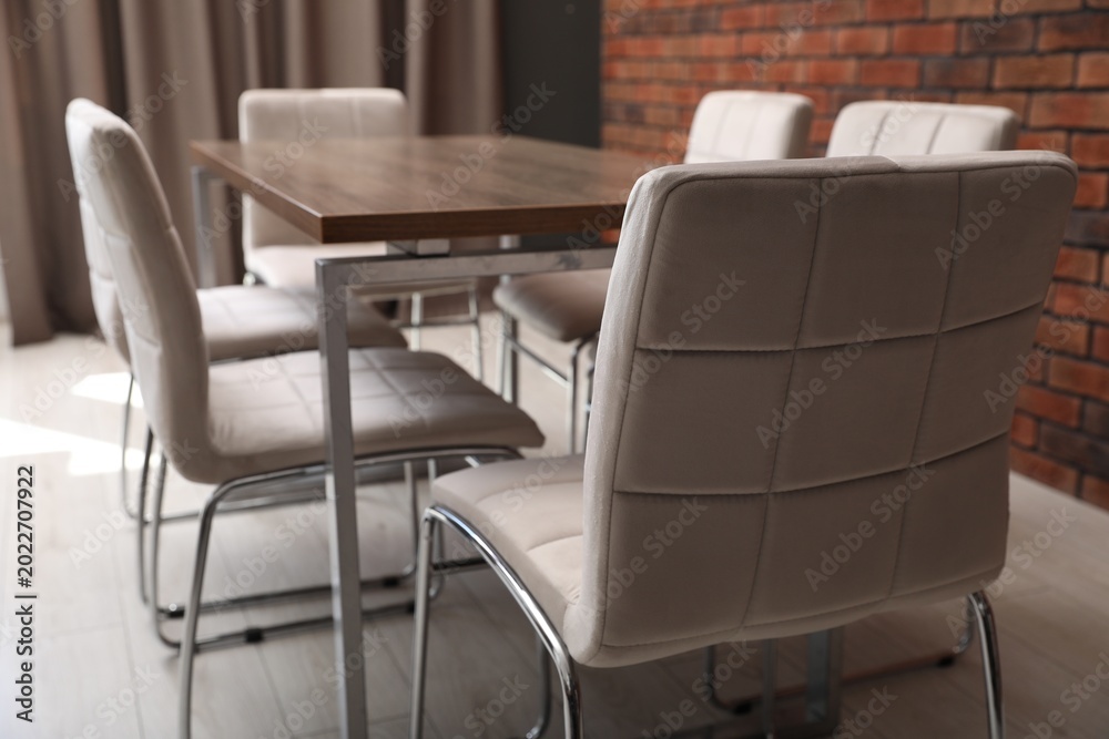 Fototapeta premium Stylish comfortable chairs and wooden table in office, closeup