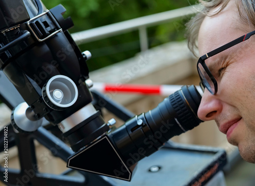 Fotografie Person looking through an astronomical telescope eyepiece, illustrating hands on optical exploration while learning the sky