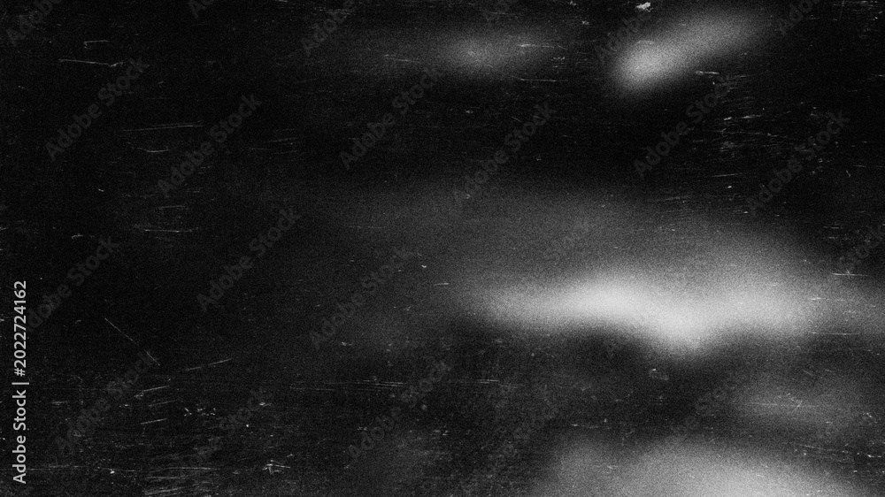 Fototapeta premium Abstract grainy monochrome background with light spots and scratch marks on black for banner.