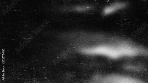 Abstract grainy monochrome background with light spots and scratch marks on black for banner.