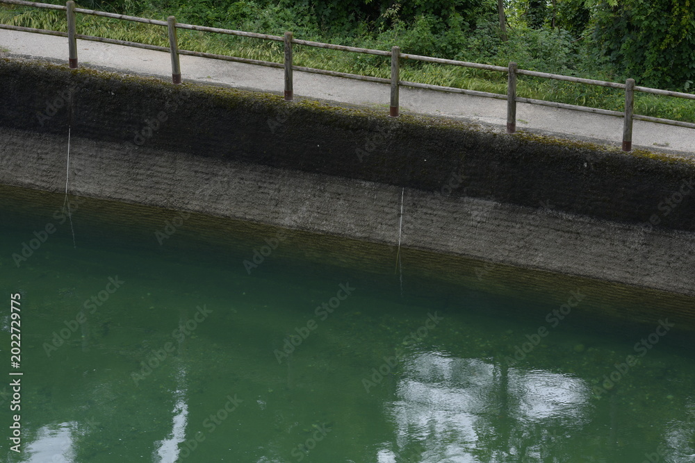 Naklejka premium Calm Canal with Green Water and Concrete Embankment 