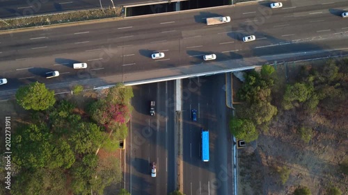 Top down drone footage of multilane freeway traffic and bridge structures in Centro Sur Queretaro, Mexico, with cinematic evening shadows and urban mobility concept