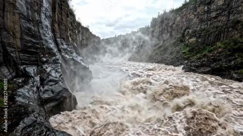 Raging mountain river crashing through steep rocky canyon walls
