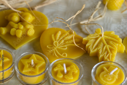 Photos closeup of various yellow natural beeswax candles and carved wax figures in shap