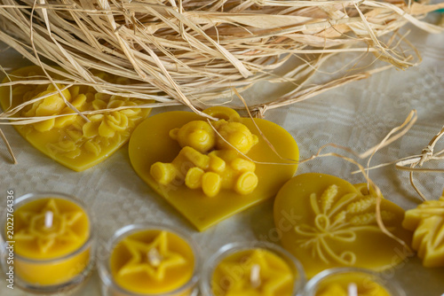 Fotografi closeup of several yellow natural beeswax candles in glass and carved wax figure
