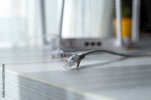 Close Up of RJ45 Ethernet LAN Network Cables on White Desk Near Modern Wireless Wi-Fi 6 Router