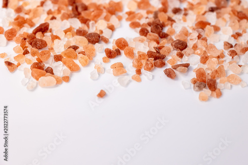 Foto Pink Himalayan salt crystals scattered on white background with copy space