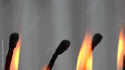 4K macro video of burning matchsticks with glowing flames and detailed charred tips.