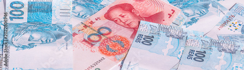Chinese Yuan banknote on the background of Brazilian 100 reais currency, concept of economic partnership.