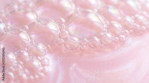 Transparent bubbles of different sizes are floating on a pink surface, creating an abstract and visually appealing background with a scientific or cosmetic feel