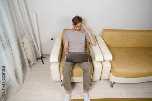 Foto An adult man works from home, sitting on the couch