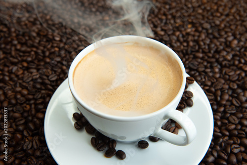 Premium dark roast arabica coffee beans with cozy cup of warm steaming and delicious coffee 