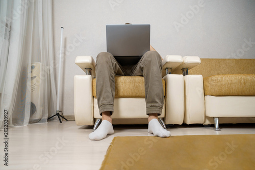 Photos An adult man works from home, sitting on the couch