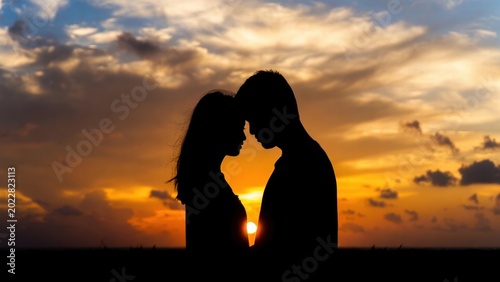 Couple facing each other at sunset on coastal horizon
