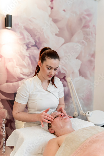 Cosmetologist applying facial skincare treatment on client face