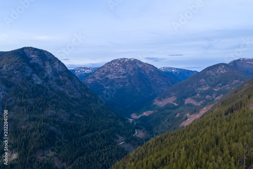 Snow-Capped Mountain Valley With Dense Evergreen Forests and Winding Road in British Columbia, Canada