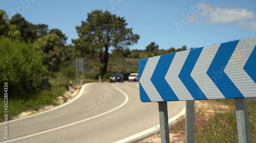 Detalle de una señal de tráfico de peligro que avisa de la proximidad de una curva en una carretera comarcal de Madrid, España. Mayo de 2026.